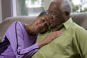 Man and woman sitting close together on sofa.