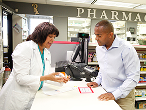 Pharmacist talking to man at pharmacy counter.